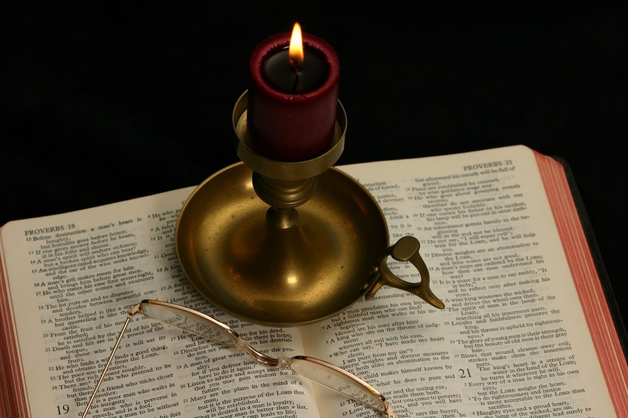 red candle on open bible Courtesy of Timothy R. NicholsShutterstockcom 2452429