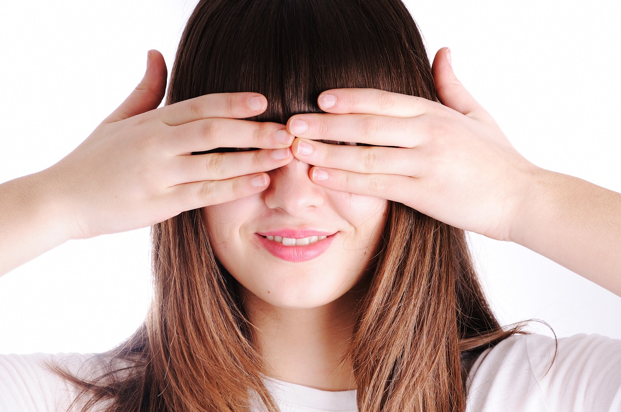 Young teen woman covering her eyes isolated on white background
